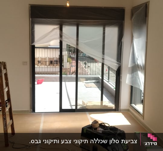 חדר עם ציוד לצביעה, דלי צבע וסולם